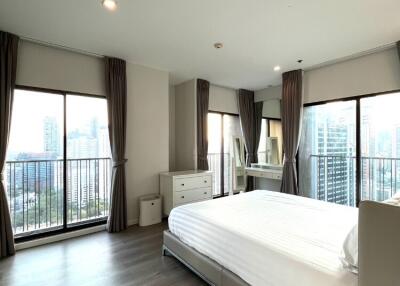 Spacious bedroom with large windows and city view