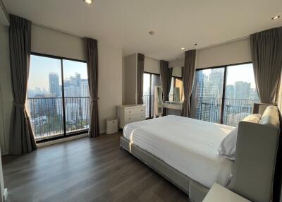 Spacious bedroom with large windows and a city view