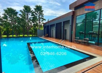 Outdoor swimming pool area with palm trees and modern building