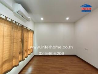 Empty bedroom with hardwood floors, beige curtains, and air conditioning unit.