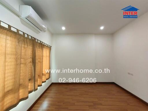 Empty bedroom with hardwood floors, beige curtains, and air conditioning unit.