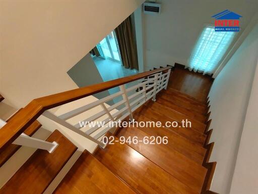 View of a wooden staircase with white railings leading to a lower floor