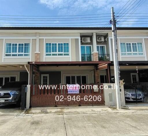 Facade of a two-story townhouse with covered driveway and a car parked in front