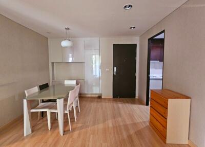 Modern minimalist dining area with table and chairs besides a chest of drawers and white cabinetry