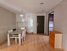 Modern minimalist dining area with table and chairs besides a chest of drawers and white cabinetry