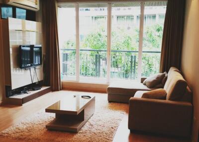 Modern living room with sofa, coffee table, TV, and large window