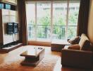 Modern living room with sofa, coffee table, TV, and large window