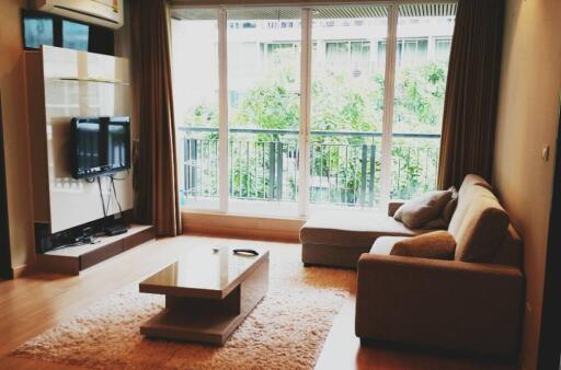 Modern living room with sofa, coffee table, TV, and large window