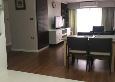 Modern living room with wooden flooring, dining table, and TV.