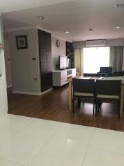 Modern living room with wooden flooring, dining table, and TV.