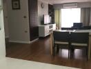 Modern living room with wooden flooring, dining table, and TV.