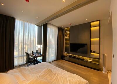 Modern bedroom with large windows, desk, and entertainment unit