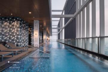 Rooftop infinity pool area with lounge chairs and city view