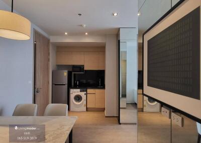 Modern kitchen area with wooden cabinets, washing machine, and dining table