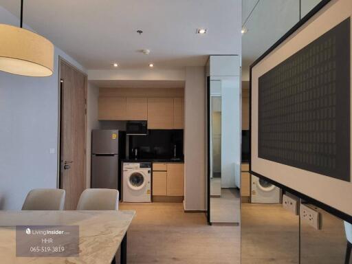 Modern kitchen area with wooden cabinets, washing machine, and dining table