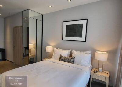 Modern bedroom with double bed, bedside tables with lamps, and large mirror