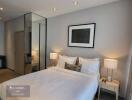 Modern bedroom with double bed, bedside tables with lamps, and large mirror