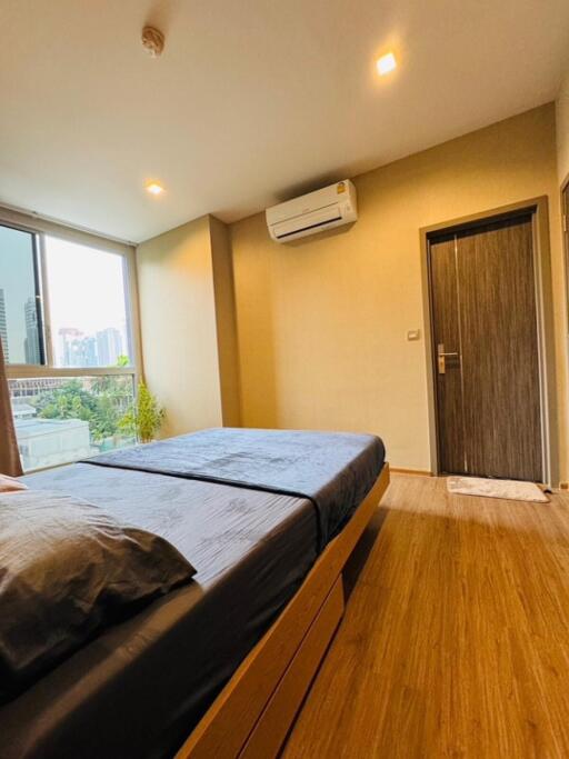 Modern bedroom with wooden flooring and large window