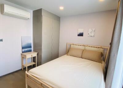 Modern bedroom with a large bed, side table, wardrobe, and air conditioner