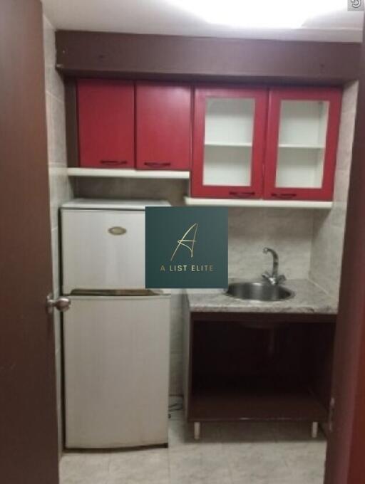 Compact kitchen with red cabinets and white fridge