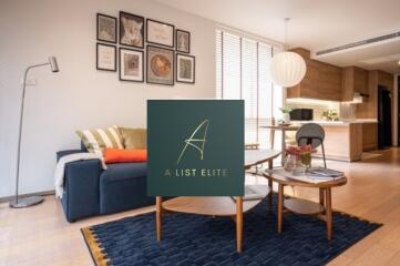 Modern living room with a sofa, coffee table, and art on the wall, adjacent to an open kitchen area