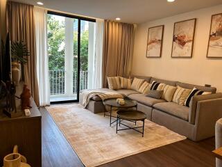 Modern and cozy living room with a large sectional sofa, coffee table, and a view of the balcony