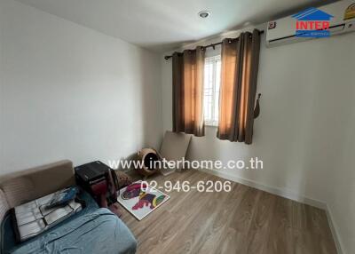 Small bedroom with wooden flooring, window with curtains, and air conditioning