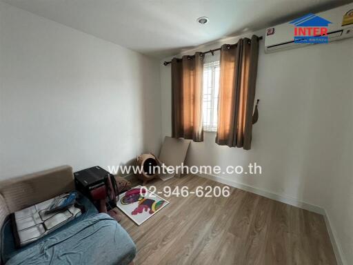 Small bedroom with wooden flooring, window with curtains, and air conditioning