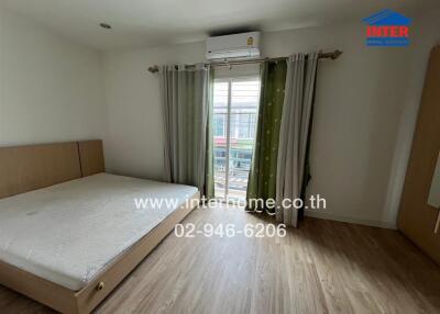 Spacious bedroom with bed, large window, and air conditioning unit