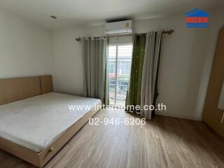 Spacious bedroom with bed, large window, and air conditioning unit