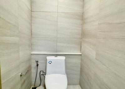 Minimalist bathroom with tiled walls and floor featuring a modern white toilet