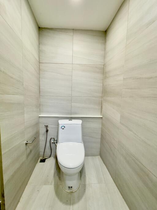 Minimalist bathroom with tiled walls and floor featuring a modern white toilet