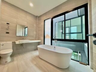 Modern bathroom with large window and standalone bathtub