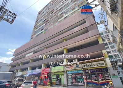 Exterior view of a commercial building with multiple floors and various shops on the ground level