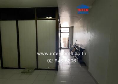 A view of a corridor area in the building, featuring a tiled floor, partition, and window.