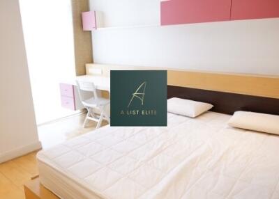 A neatly arranged bedroom with a bed, study desk, and wall cabinets