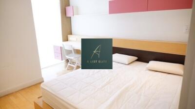 A neatly arranged bedroom with a bed, study desk, and wall cabinets