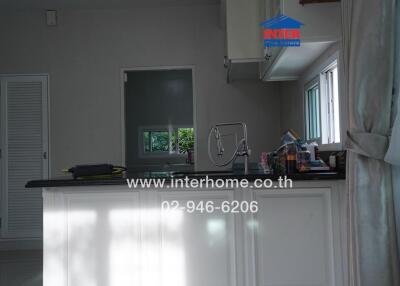 Modern kitchen area with large window and white cabinetry