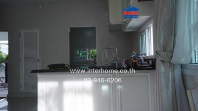 Modern kitchen area with large window and white cabinetry