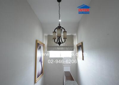 Narrow hallway with chandelier and framed pictures