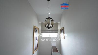 Narrow hallway with chandelier and framed pictures