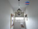 Narrow hallway with chandelier and framed pictures