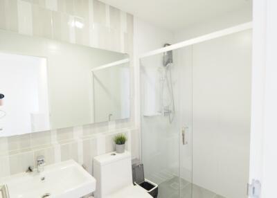 Modern bathroom with glass shower, toilet, and sink