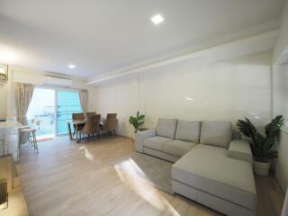 Modern living room with grey sectional sofa, dining area, and balcony access