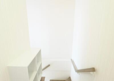 Well-lit staircase with wooden steps and a built-in white bookshelf