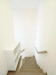 Well-lit staircase with wooden steps and a built-in white bookshelf