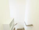 Well-lit staircase with wooden steps and a built-in white bookshelf