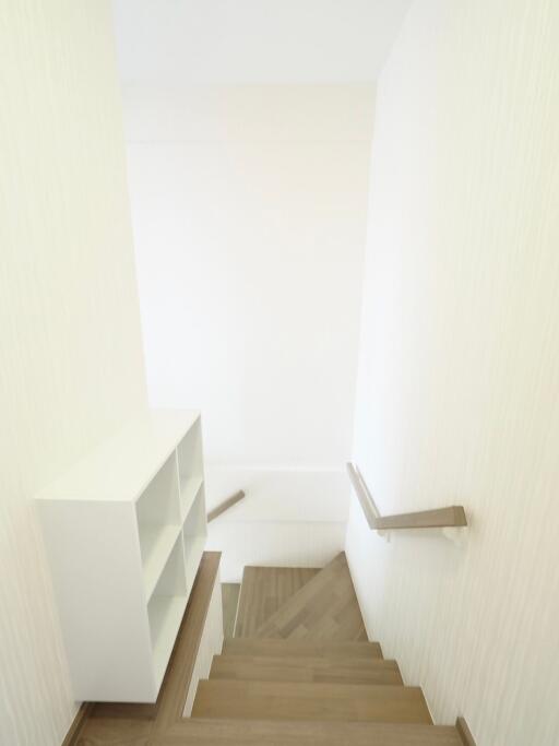 Well-lit staircase with wooden steps and a built-in white bookshelf