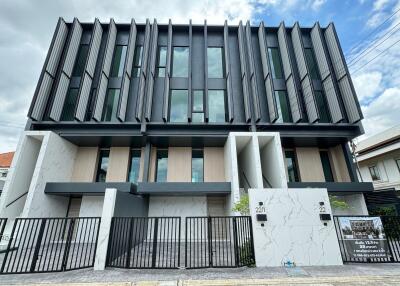 Modern multi-story residential building with large windows and gated entrance