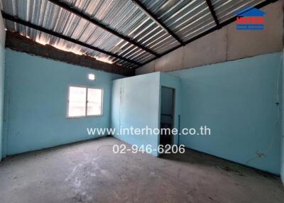 Empty room in a building with metal roofing and blue walls